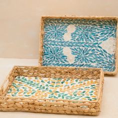 two woven trays sitting on top of a white table next to eachother