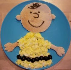 a child's plate with scrambled eggs, black olives and a smiling face