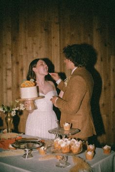 a bride and groom feeding each other cake at their wedding reception in front of a wood paneled wall