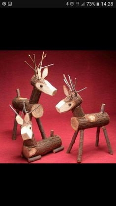 two wooden reindeer sculptures sitting next to each other on a red background, one is made out of logs