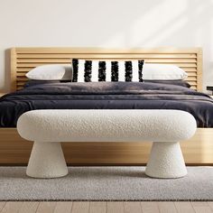 a bed with two black and white pillows on it's headboard next to a bench