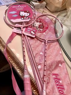 two pink hello kitty tennis racquets on top of a table next to each other