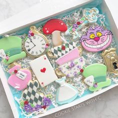 a box filled with lots of decorated cookies in the shape of alice and wonderland characters