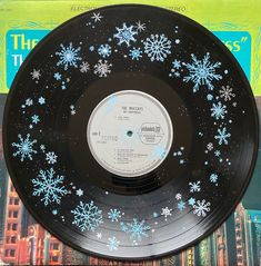 a record with snowflakes on it sitting on top of a book shelf next to a pile of books