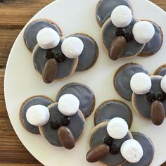 four decorated cookies on a plate with marshmallows in the shape of a koala bear