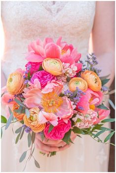 a bridal holding a bouquet of pink and yellow flowers with greenery in the foreground