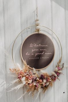 an embroidery hoop with a quote on it hanging from the side of a wooden wall