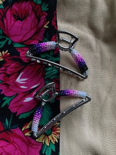 three pairs of scissors are sitting on a flowered fabric with pink and purple beads