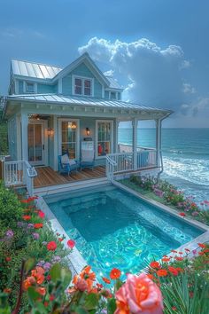 a house with a pool in front of it next to the ocean and flowers on the ground