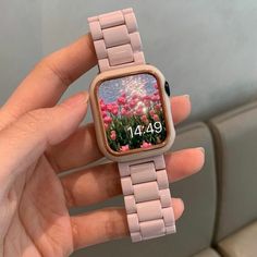 a person holding an apple watch with pink flowers on the screen and numbers displayed on it