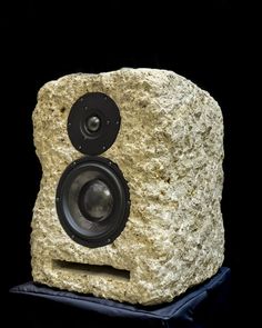 a large rock with speakers on it's side, sitting on a black surface