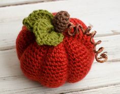 there is a knitted pumpkin with leaves on it's head and two acorns attached to the top