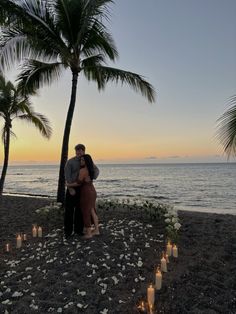 a couple kissing on the beach with candles in front of them