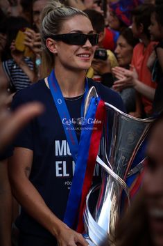 a woman holding a silver cup in front of a crowd