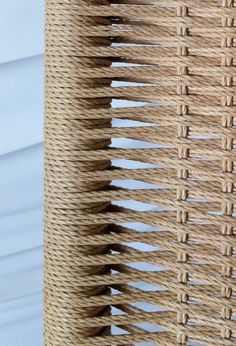 close up view of woven material on the back of a wicker chair with white walls in the background