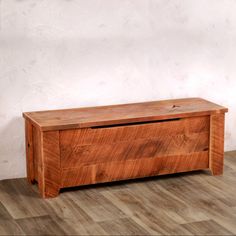 a wooden chest sitting on top of a hard wood floor next to a white wall