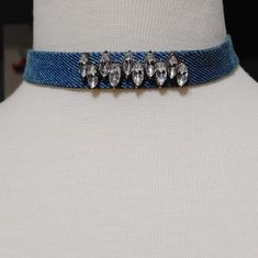 a white mannequin wearing a blue choker with crystal stones on the bottom