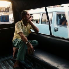 a man sitting in the back of a pick up truck with his hand on his chin