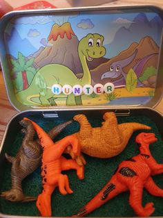 an open tin box with dinosaur toys in it