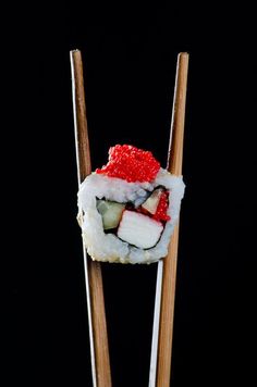 two chopsticks with sushi on them, one is red and the other is white