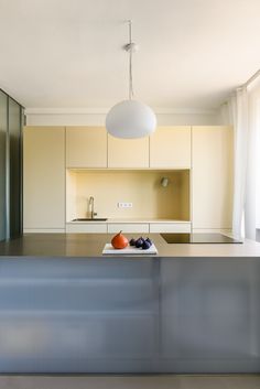 a modern kitchen with stainless steel countertops and white cabinetry, along with an island in the middle