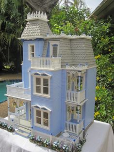 a blue doll house sitting on top of a table next to a pool and trees