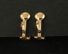 two pairs of gold colored earrings sitting on top of a black surface