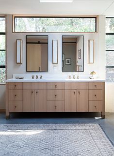 a bathroom with double sinks and mirrors in the middle, along with large windows on both sides