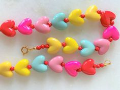 "Kids Brite Multi Colored Plastic Heart Necklace with Red Mini Spacer Beads Gold Tone Spring Ring Clasp Closure Brite Multi Hearts are Red, Hot Pink, Pink, Aqua, Yellow Hearts Measure 5/8\" Wide Necklace Measures 15\" Imported COMPLIMENTARY DOMESTIC SHIPPING" Multicolor Beaded Jewelry For Valentine's Day, Playful Heart Beads For Jewelry Making, Valentine's Day Multicolor Beaded Jewelry, Valentine's Day Playful Beaded Jewelry, Adjustable Multicolor Heart Charm Necklace, Adjustable Multicolor Heart Pendant Necklace, Adjustable Multicolor Heart Necklace, Adjustable Multicolor Necklace With Heart Charm, Playful Jewelry With Heart Beads