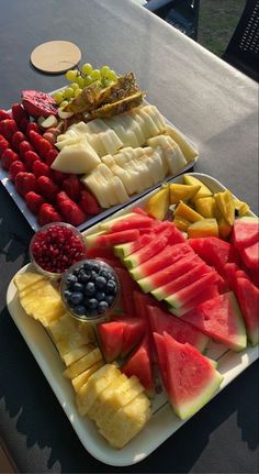 two trays filled with different types of fruit on top of a table next to each other