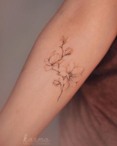 a woman's arm with flowers on it, and the tattoo is done in black ink