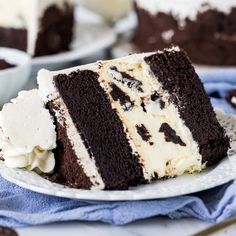 a slice of chocolate cake on a plate next to a knife and fork with the rest of the cake in front of it