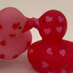 two pink rubber ducks with hearts on them, one is kissing the other's head