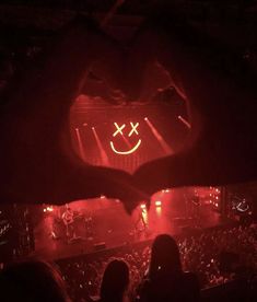 a heart shaped neon sign in the middle of a stage with people sitting around it