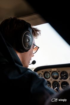 a man wearing headphones sitting in the cockpit of a plane