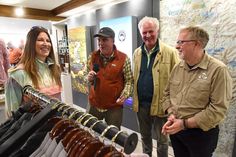 three men and two women standing in front of a display of shirts