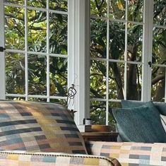 a living room filled with furniture and lots of windows covered in glass doors that look out onto the trees