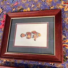 an image of a fish framed in a wooden frame on a floral wallpaper background