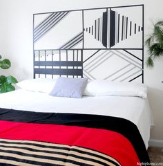 a bed with white sheets and black headboard next to a potted palm tree