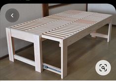 a wooden bed frame sitting on top of a hard wood floor next to a wall