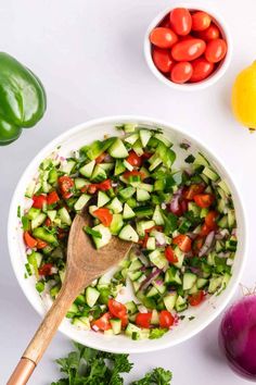 cucumber and tomato salad in a bowl with a wooden spoon next to it