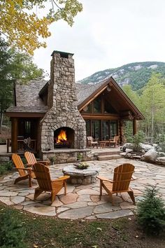 a stone patio with two chairs and a fire place in front of a cabin style building