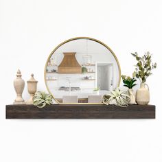 a mirror sitting on top of a wooden shelf next to vases and potted plants