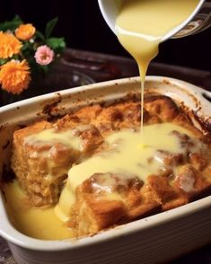 a white dish filled with bread and cheese being drizzled on top of it