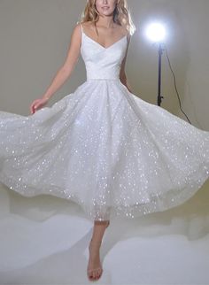 a woman in a white dress is posing for a photo with a light behind her