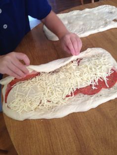 a person making pizza dough on top of a wooden table