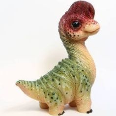 a small toy dinosaur with spots on it's head and neck, standing upright