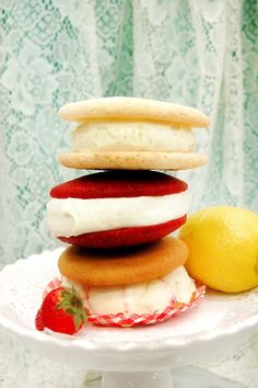 a stack of cookies, ice cream and strawberries on a cake plate with a lemon