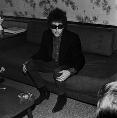 a man sitting on top of a couch in a living room next to a table