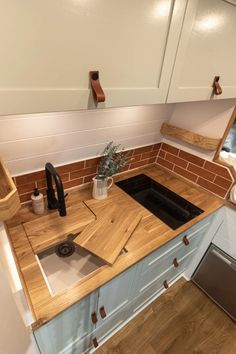 a kitchen with wooden counter tops and white cupboards next to a stove top oven